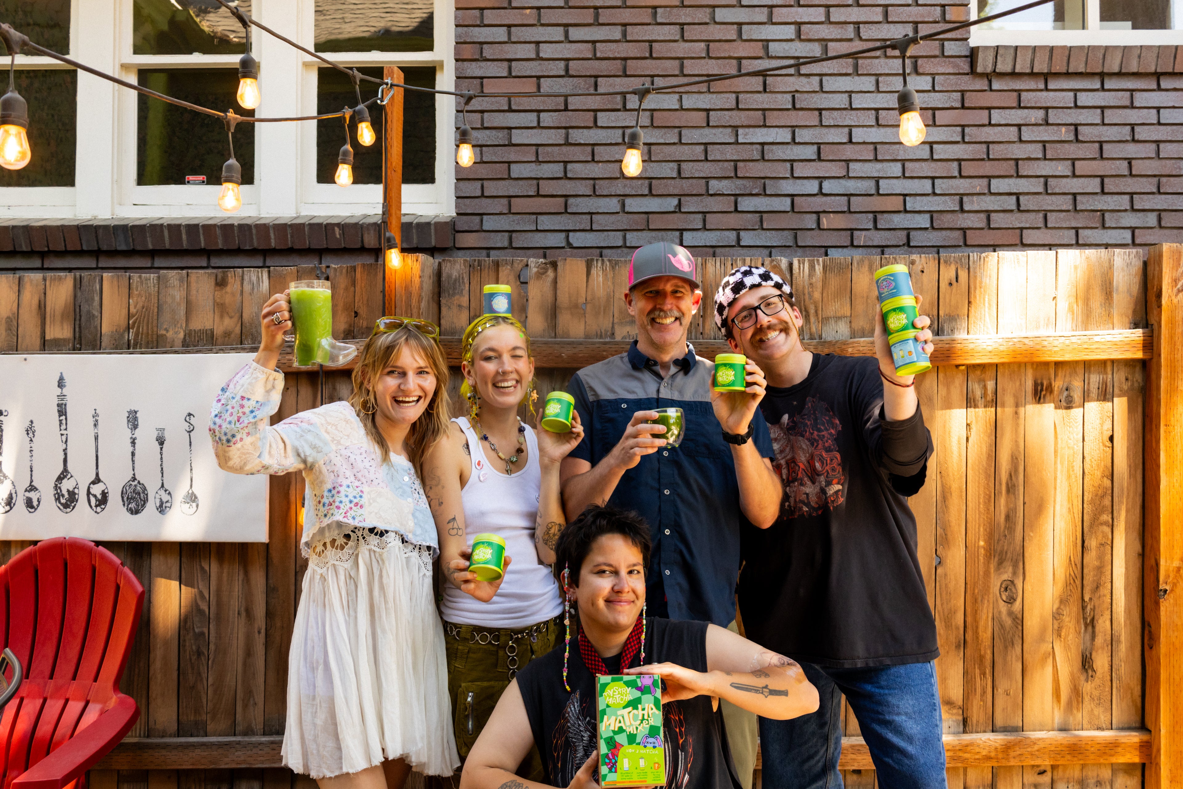 our quirky, eclectic band of queers, five people holding mystry matcha products including matcha tins and the mystry mixer